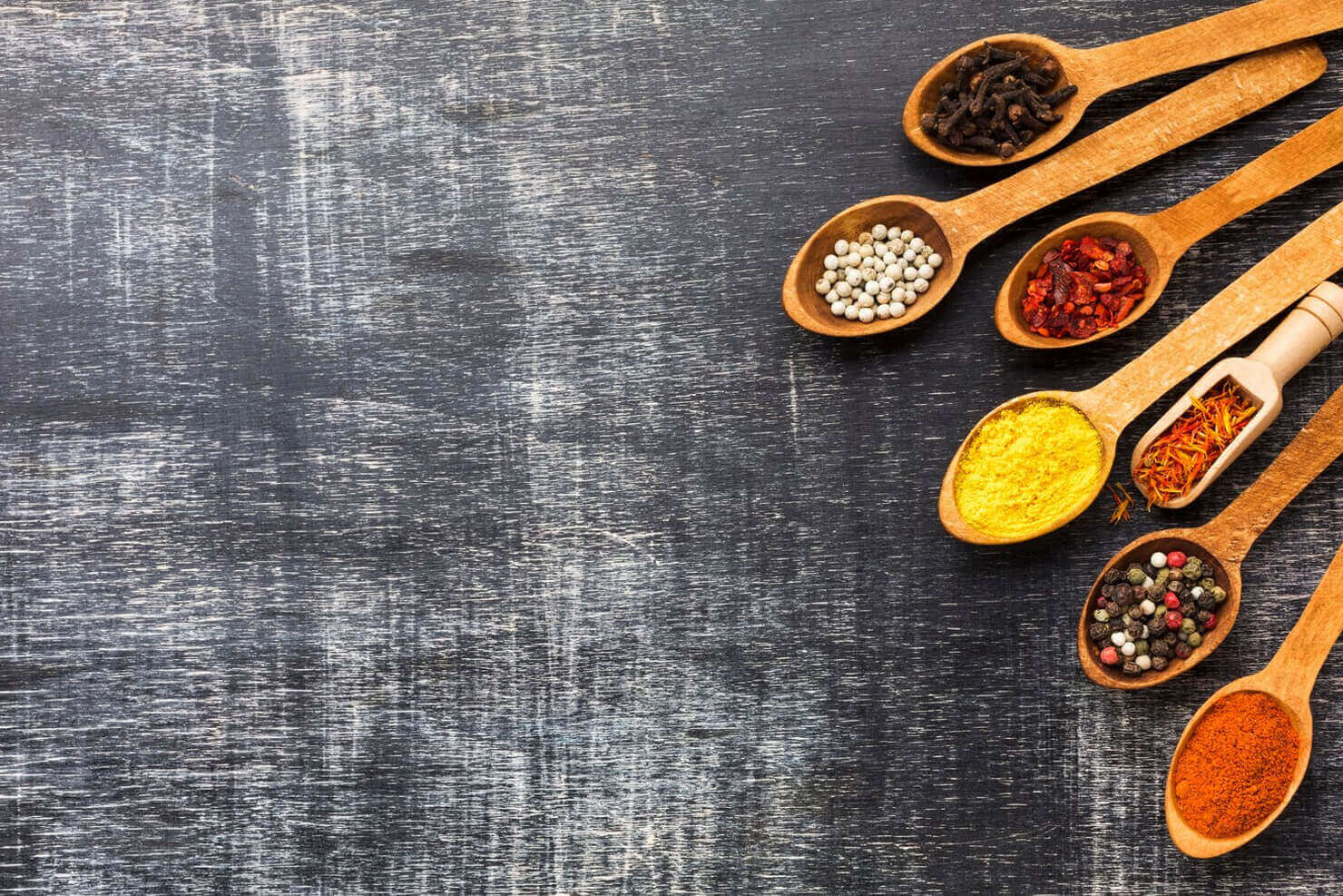 Assorted Indian spices in bowls—turmeric, chili, cumin—top view on a rustic background.